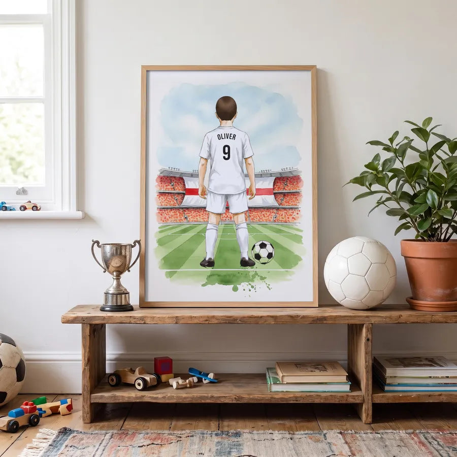 A personalised football player print in an oak frame on a shelf with a trophy and a football